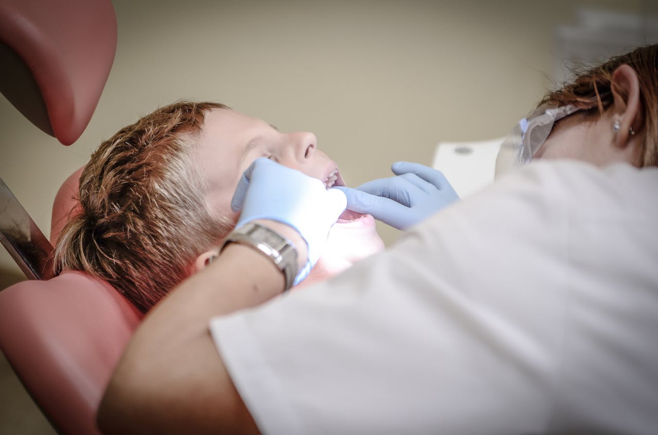 why-choose-us A young boy receiving a dental examination by a professional dentist in a clinic setting.